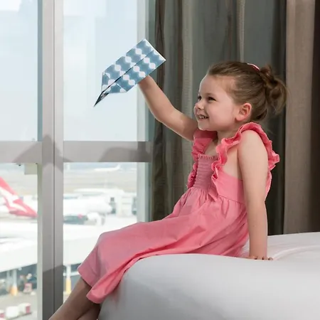 Rydges Sydney Airport Hotel Exterior photo The child is playing with a paper airplane.